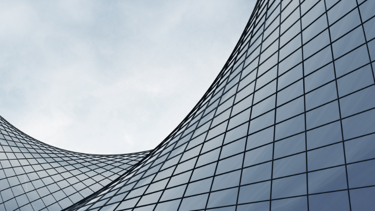 Curved building windows in front of clear blue sky.